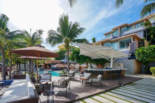 un patio al aire libre con sillas, mesas y sombrillas en Bandara Villas, Phuket en Panwa Beach