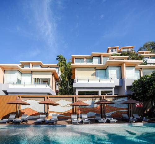 a hotel with a swimming pool with chairs and umbrellas at Bandara Pool Villas, Phuket in Panwa Beach