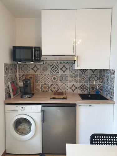 une cuisine avec un lave-linge et un micro-ondes dans l'établissement Studio 4 personnes avec jardinet à 2 pas des plages 