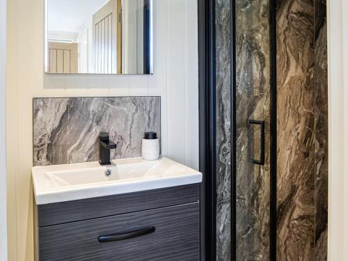 W łazience znajduje się umywalka i lustro. w obiekcie The Seaview Snug w mieście Whithorn