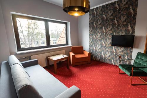 a living room with a couch and a chair and a window at Hotel Podkowa in Wrocław