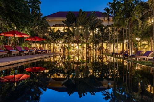 basen z leżakami i parasolami obok budynku w obiekcie Pavillon d'Orient Boutique Hotel w Siem Reap