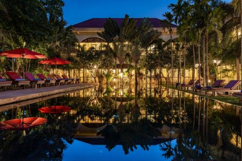 - une piscine avec des chaises et des parasols à côté d'un bâtiment dans l'établissement Pavillon d'Orient Boutique Hotel, à Siem Reap