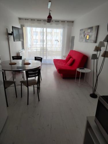 a living room with a red couch and a table at Appartement 2 Pièces avec une grande terrasse, 3 étoiles, Wifi, Box pour véhicule et vélos in Les Sables-dʼOlonne