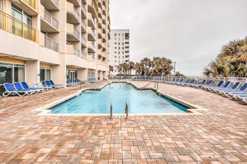 a swimming pool with blue lounge chairs and a hotel at Oceanfront Resort Condo in North Myrtle Beach in Myrtle Beach