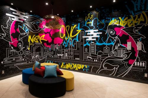 a room with a wall with a mural of a city at Just Sleep Osaka Shinsaibashi in Osaka