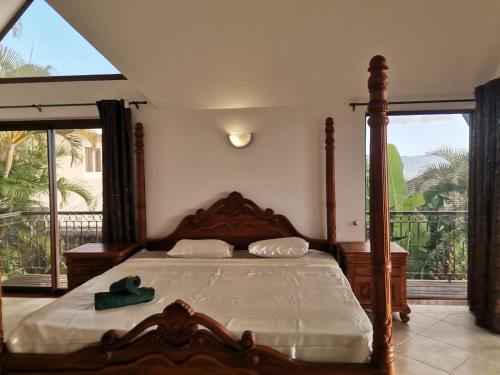 Villa with 6 bedroom en-suite في ريفير نوار: غرفة نوم بسرير خشبي ونافذة كبيرة