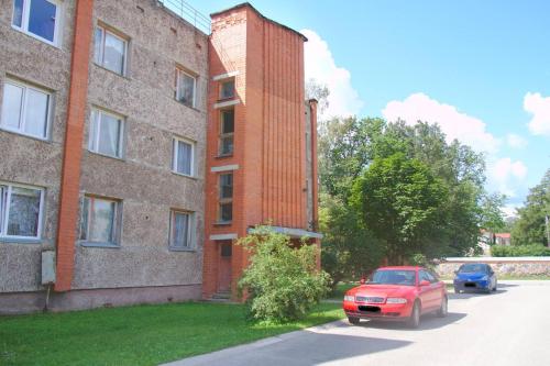 un coche rojo estacionado junto a un edificio de ladrillo en Fejas Dzīvoklis, en Vecpiebalga