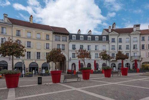 un gran edificio con macetas de flores rojas delante de él en Place Toscane Disney dream III BMYGUEST, en Serris