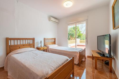 a bedroom with two beds and a flat screen tv at Villa Nevada in Pollença