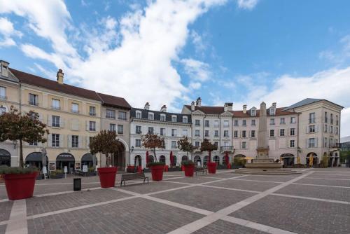 un grand bâtiment avec des pots rouges dans une cour dans l'établissement Place Toscane Disney dream III BMYGUEST, à Serris