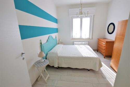 サン·ヴィンチェンツォにあるColombo apartment, fronte spiaggiaの青と白のベッドルーム(ベッド1台、窓付)