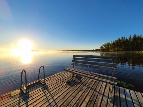 a bench sitting on a dock on a lake at Lomamokkila Cottages in Savonlinna