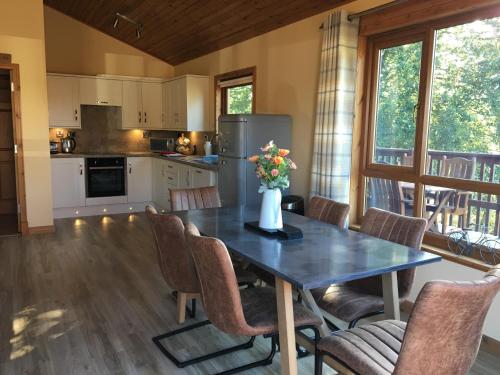a kitchen and dining room with a table and chairs at Silver Birch Lodge with Hot Tub in Cupar