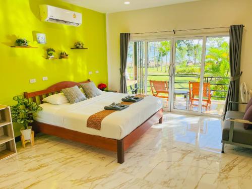a bedroom with a bed with yellow walls and a balcony at Rimlay Bay View in Ko Yao Noi