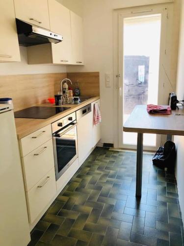 une cuisine avec des armoires blanches et un sol carrelé dans l'établissement Appart T2 vue imprenable sur le canal et la mer, à Port-la-Nouvelle