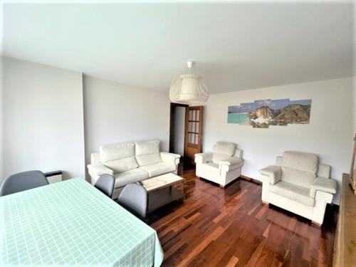 een slaapkamer met een bed en 2 stoelen en een bank bij playa Santa Cristina in Oleiros