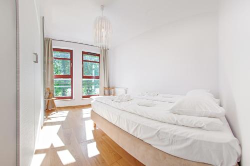 a white bedroom with a large bed and a window at Apartamenty Sun & Snow Kamienice Nad Motławą in Gdańsk
