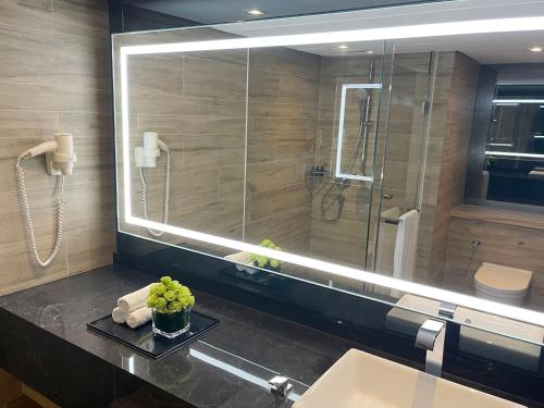 La salle de bains est pourvue d'un lavabo et d'un grand miroir. dans l'établissement Prince Hotel, Marco Polo, à Hong Kong