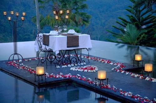 a table with candles sitting on a table in the water at Jungle Retreat by Kupu Kupu Barong in Ubud