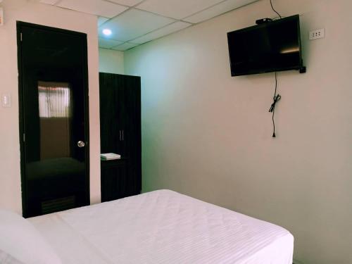 a bedroom with a bed and a flat screen tv at Anton's Inn in Balanga