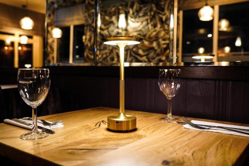 a table with two wine glasses and a lamp on it at Gwydyr Hotel in Betws-y-coed