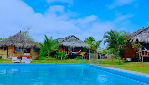 a resort with a swimming pool and some huts at Kamala Surf & Backpacker Hostel in Montañita
