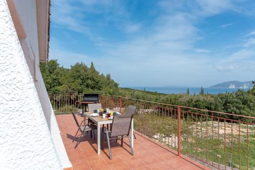 a patio with a table and chairs on a balcony at Salty Pebble House in Fiskardho