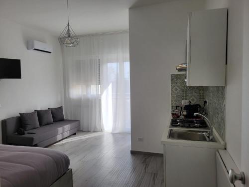 a white kitchen with a sink and a couch in a room at Casa al Mare in Bari