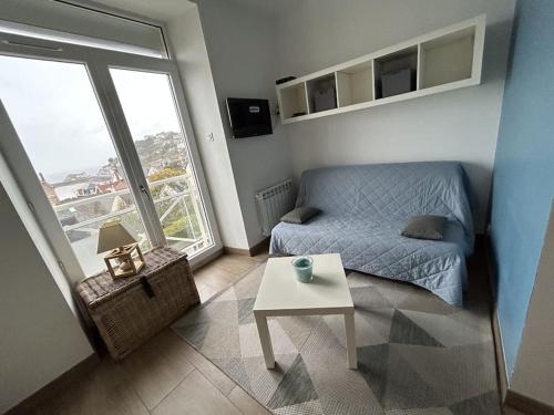 una pequeña sala de estar con sofá y mesa. en Le Cocon Bleu - Vue mer, en Pléneuf-Val-André