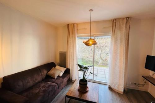 uma sala de estar com um sofá e uma janela em Spacious and very central apartment with garden em Vannes