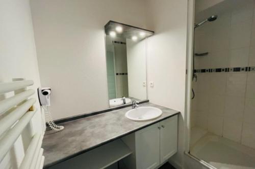 uma casa de banho com um lavatório, um chuveiro e um espelho. em Spacious and very central apartment with garden em Vannes