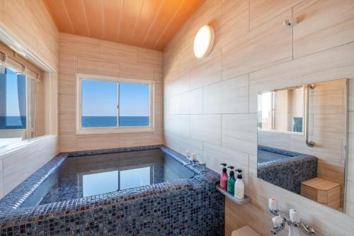 a bathroom with a large tub with a window at Umino Hotel Hajime in Beppu