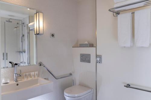 a white bathroom with a toilet and a sink at Hôtel Gustave in Paris