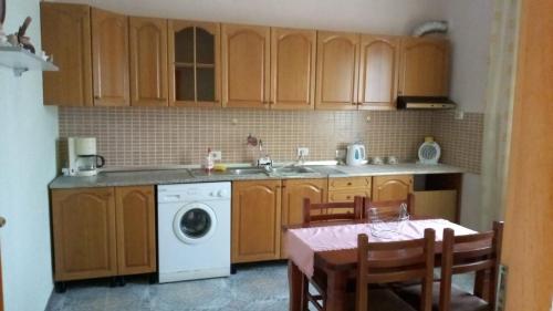 a kitchen with wooden cabinets and a table and a washing machine at Sonce - Tirana in Tirana