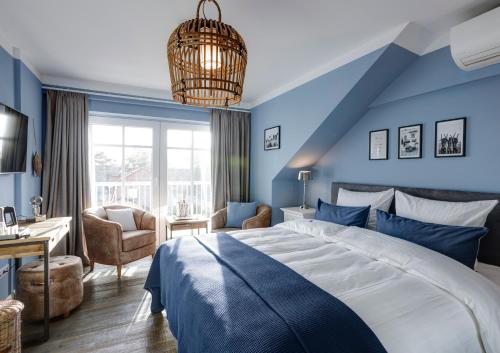 - une chambre avec des murs bleus, un lit et un bureau dans l'établissement Seventy Seven Beach Hotel, à Timmendorfer Strand