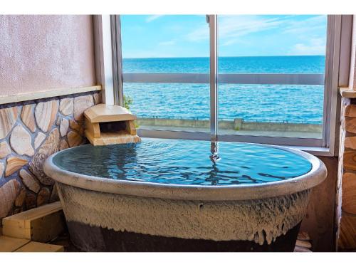 a large bath tub with a view of the ocean at Umino Hotel Hajime in Beppu