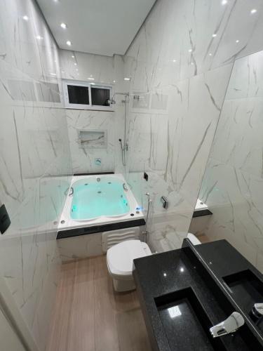 ein Badezimmer mit einer Badewanne, einem WC und einem Waschbecken in der Unterkunft Ônix Hotel in Assis