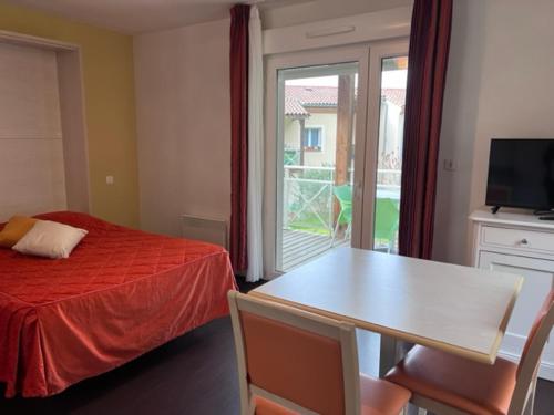 a bedroom with a bed and a table and a window at Les bords de l'Aveyron in Nègrepelisse