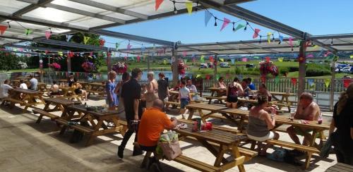 een groep mensen die aan picknicktafels zitten bij Gateway Glamping Pods in Llanelli