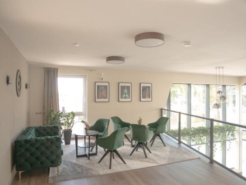 a living room with a table and green chairs at Dominik Hotel & Eventsaal in Paderborn