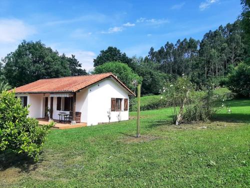 una pequeña casa blanca en un campo con árboles en La Rotiza, en La Collada