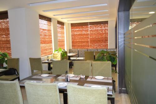 a dining room with a table and chairs and windows at Sobti Continental Bareilly in Bareilly