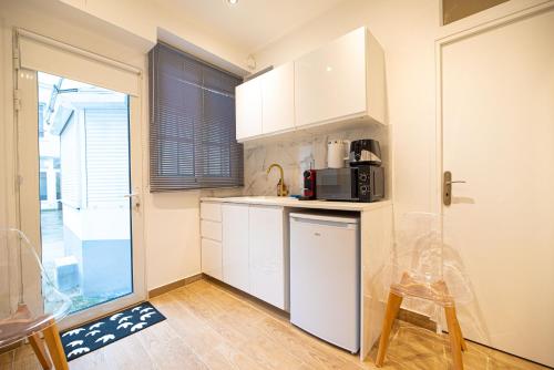 une cuisine avec des placards blancs, une table et un tabouret dans l'établissement Cosy studio on bastille, à Paris