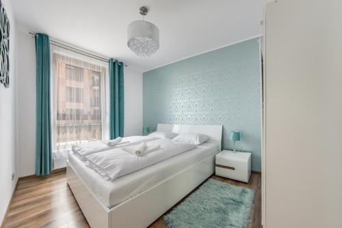 a bedroom with a large white bed and a window at Apartamenty Sun & Snow Front Park in Gdańsk