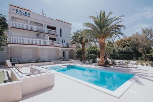 a villa with a swimming pool in front of a building at Seagull Pool Apartments & Studios in Novalja