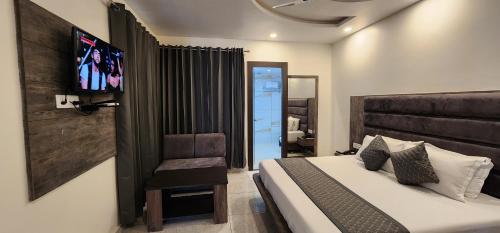 - une chambre avec un lit et une télévision murale dans l'établissement Hotel The Vaishvik, à Katra