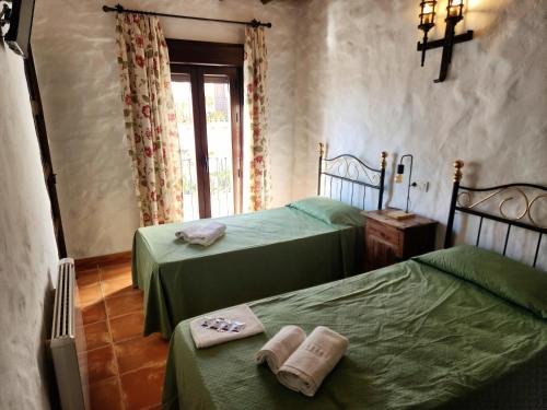 two beds in a room with green sheets and towels at Posada La Plaza in Canillas de Albaida