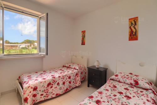 a bedroom with two beds and a window at Gold Beach House by LoveSud in Torre Pali 