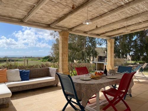 a patio with a table and chairs and a couch at Gold Beach House by LoveSud in Torre Pali 